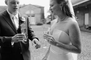 A black and white wedding photo shows a couple sharing champagne together during their celebration.