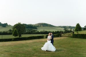 Serene rolling hills with scattered trees form the backdrop for a joyful couple celebrating their wedding day outdoors.