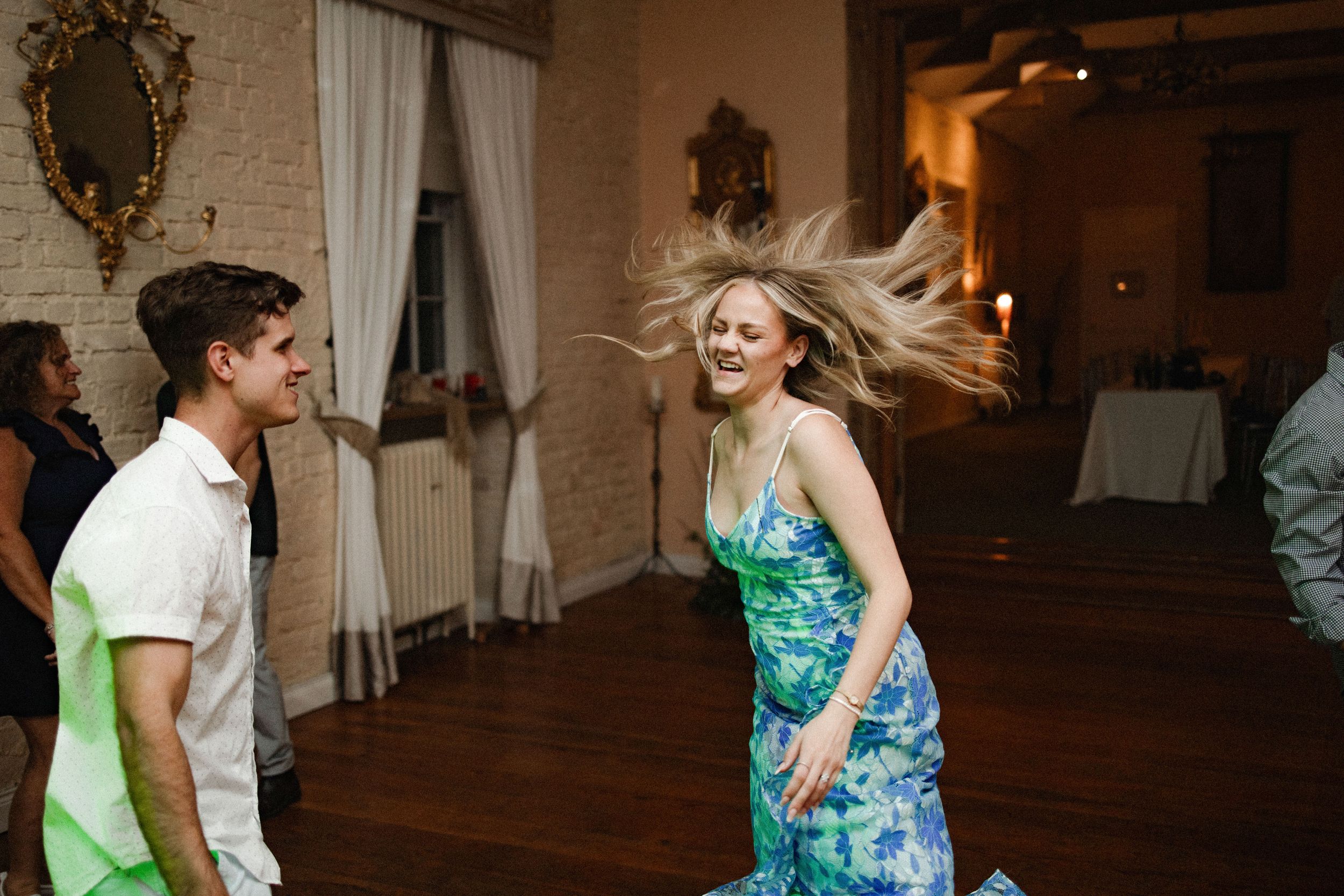 Two people dance together during an evening celebration in an elegant indoor venue with warm lighting.