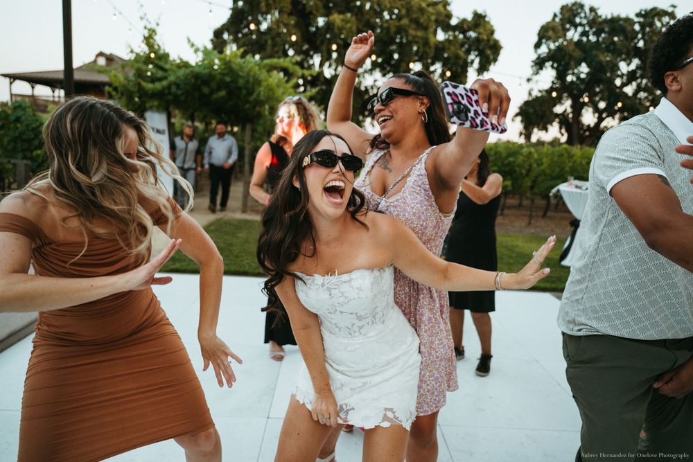 Group of friends dancing and celebrating outdoors on a white dance floor at a summer party.