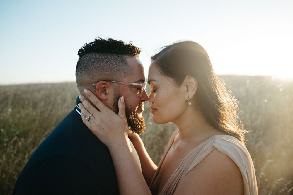 Romantic couple sharing an intimate moment in a sunlit field during golden hour.
