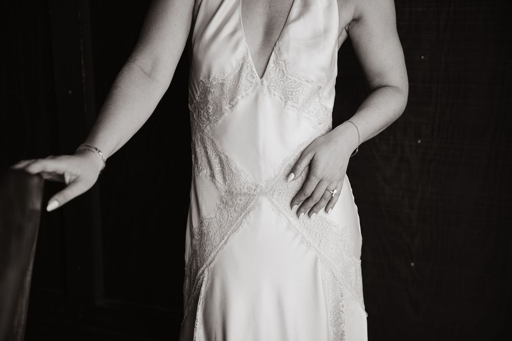 Black and white photo of a person wearing an elegant vintage white slip dress with delicate lace details.
