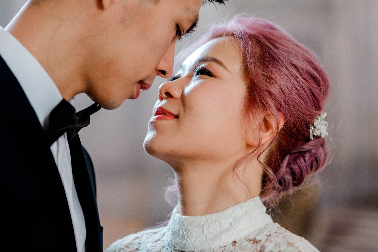 A romantic wedding photo shows a couple in formal attire sharing an intimate close-up moment together in San Francisco City Hall.