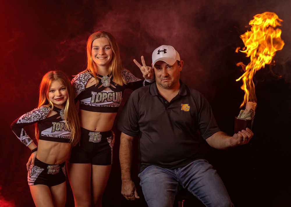 Group poses with flaming props in matching uniforms against dramatic red background.
