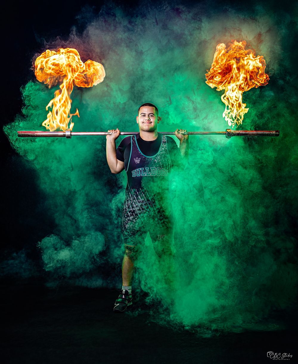 A dramatic sequence showing fire effects and green smoke during a weightlifting performance in a dark setting.