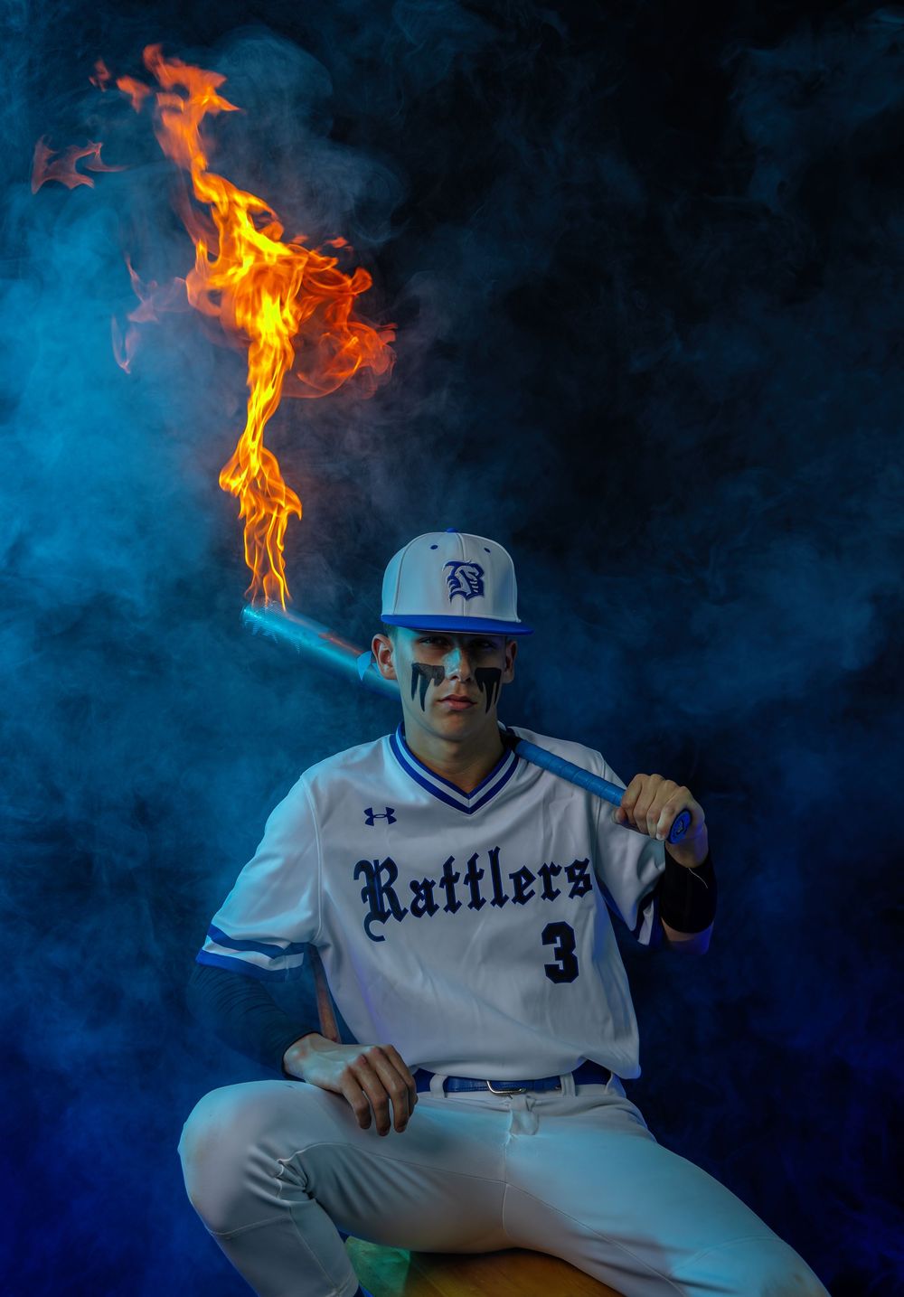 Baseball player in Rattlers uniform poses with flame effect against blue backdrop.