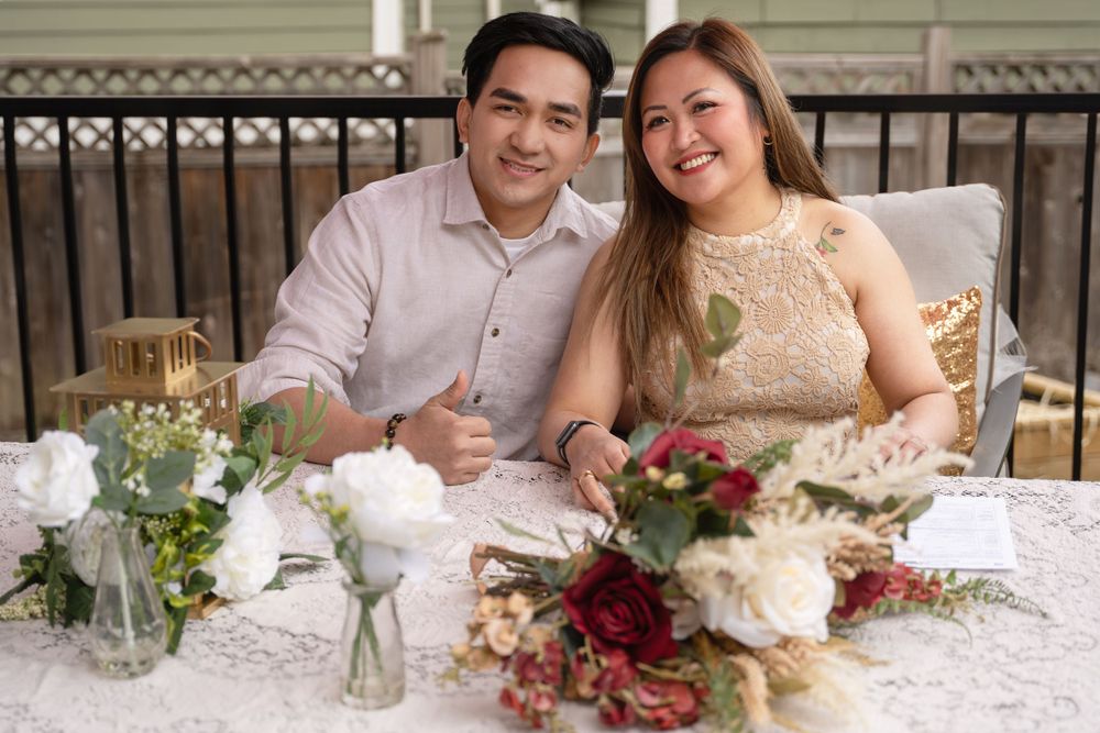 Couple at wedding reception table with elegant floral decorations and lace tablecloth.