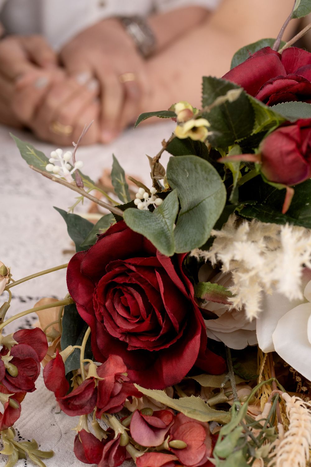 Close-up of deep red roses and greenery in an elegant wedding bouquet arrangement.