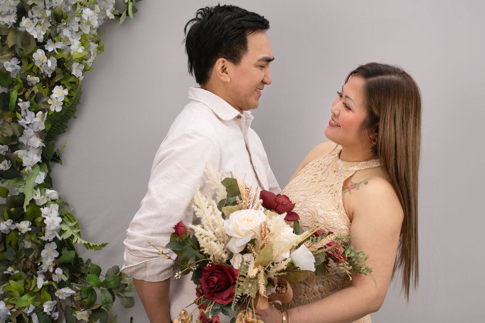 Romantic wedding portrait with couple holding bouquet of red and white flowers.