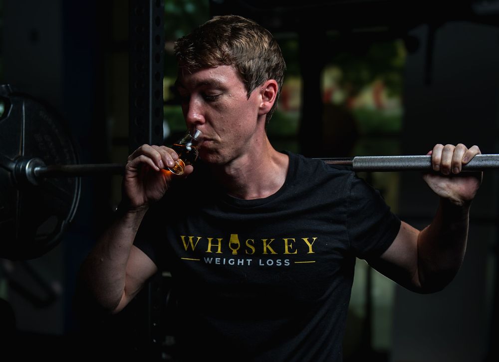 Athletic person performing weighted dumbbell walking lunges in a dimly lit fitness studio.