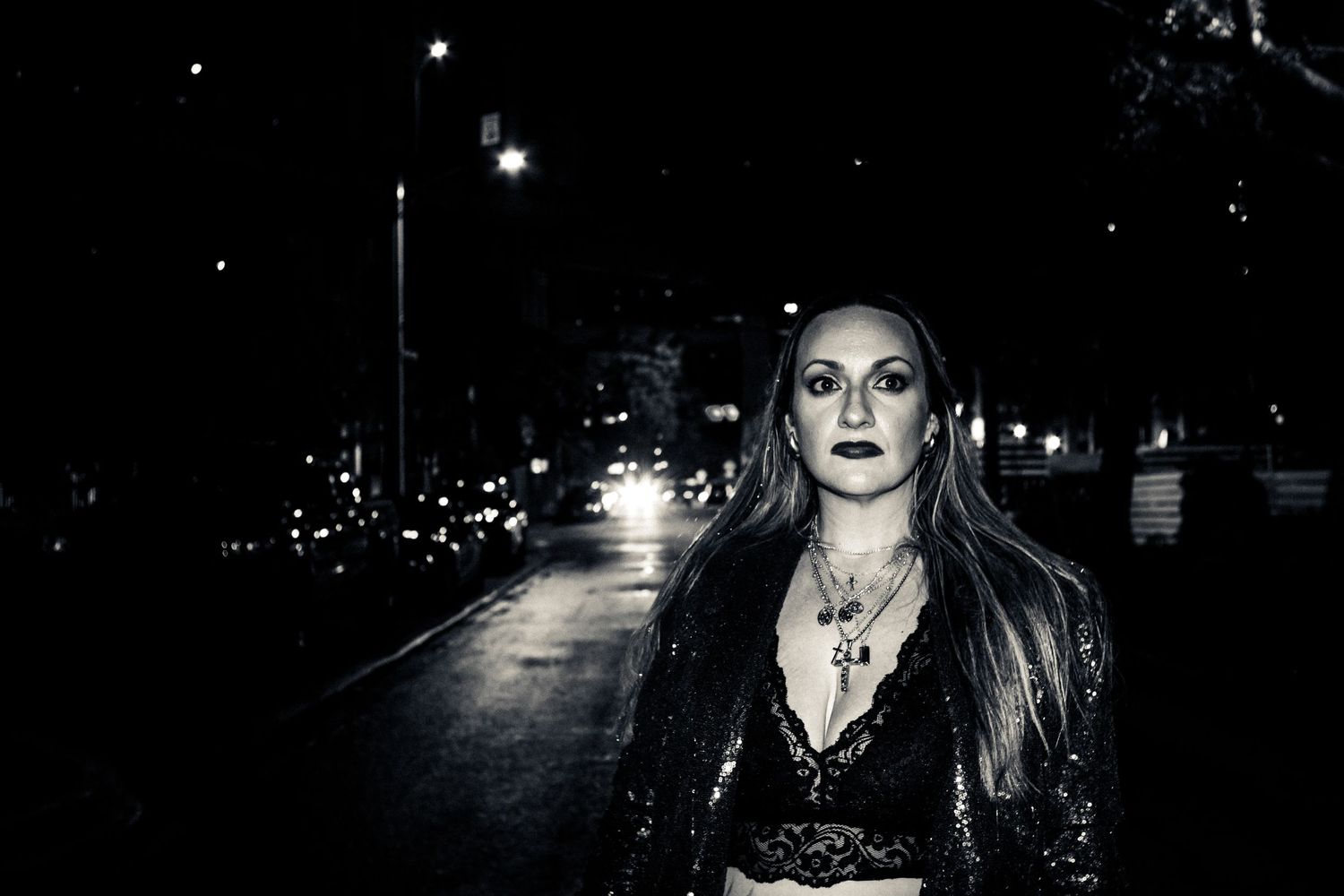 Dramatic nighttime portrait on a dark city street illuminated by street lights.
