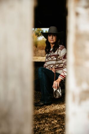 A person in a black hat and striped sweater poses thoughtfully in a series of artistic outdoor portrait shots.