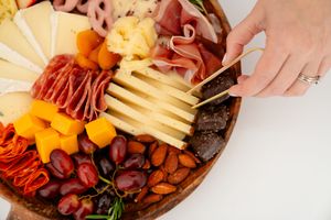 A wooden charcuterie board filled with meats, cheeses, fruits, and nuts arranged in an appetizing display pattern.
