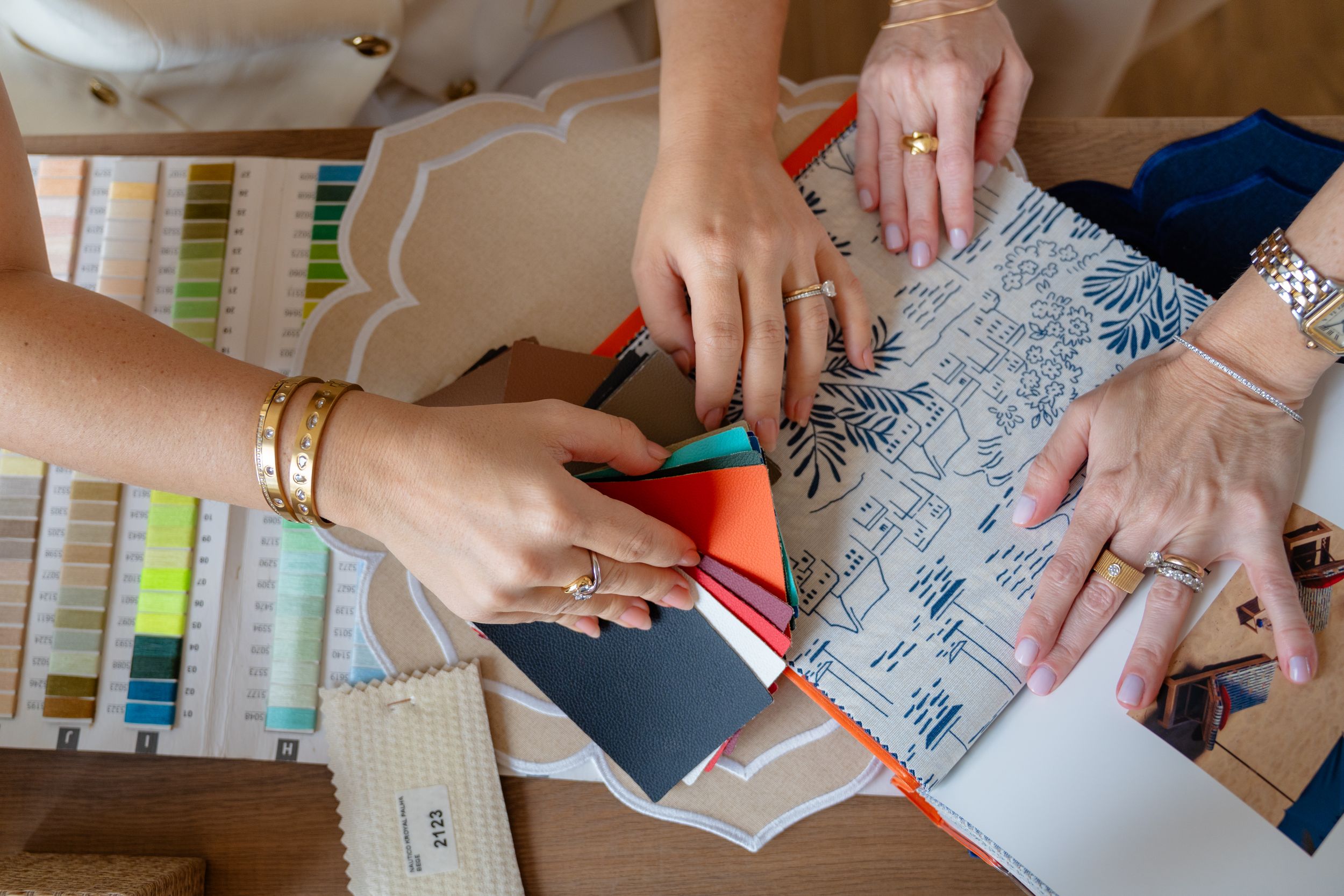 Two designers collaborate over fabric swatches and pattern samples on a wooden table in a design studio.