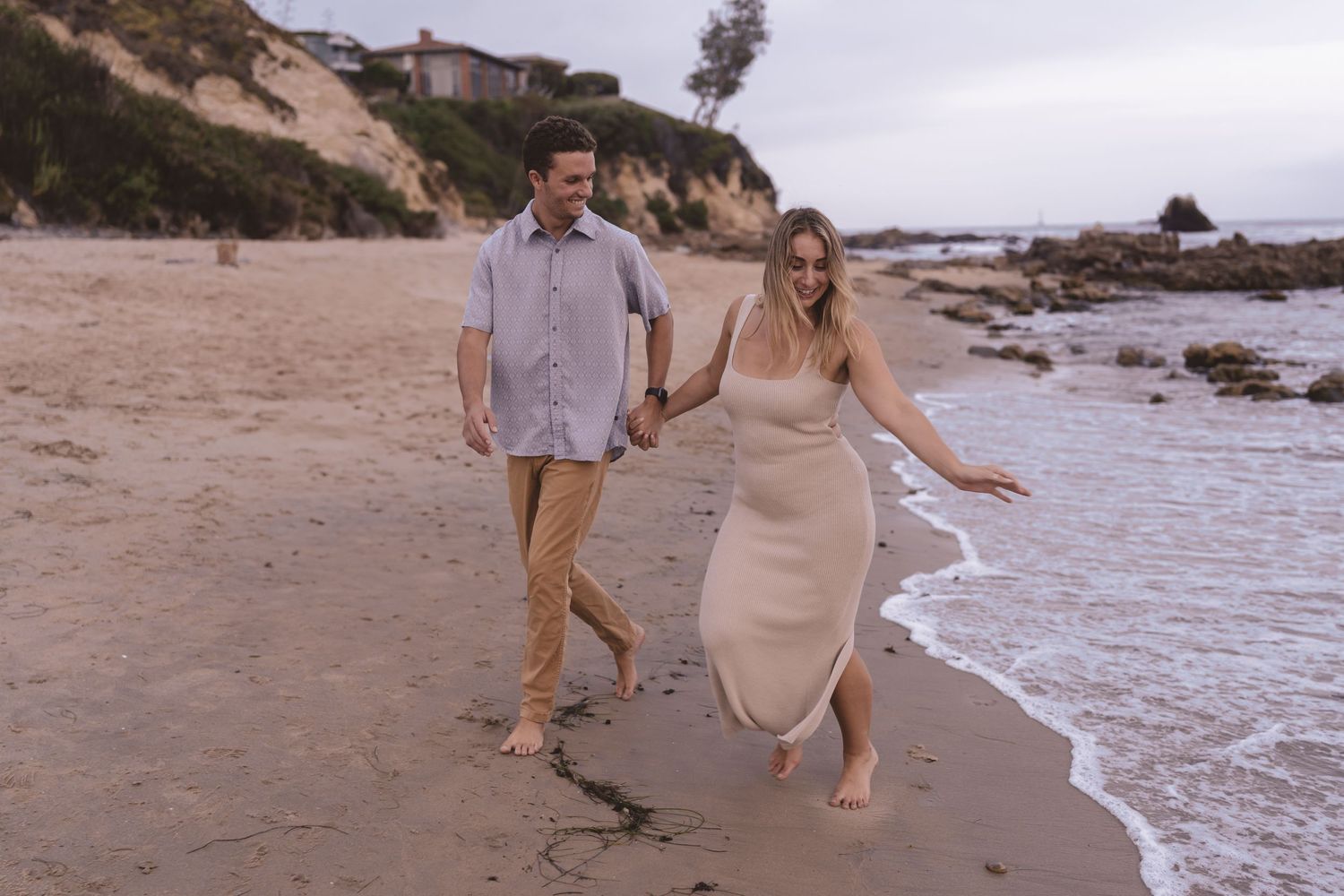 Couple running on the sand alongside the ocean in southern California. destination photographer