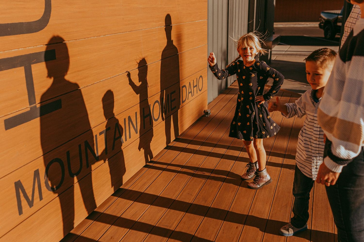 Shadows cast on orange wall while people stand on stage during golden hour sunset lighting. Whitney Popp photographer