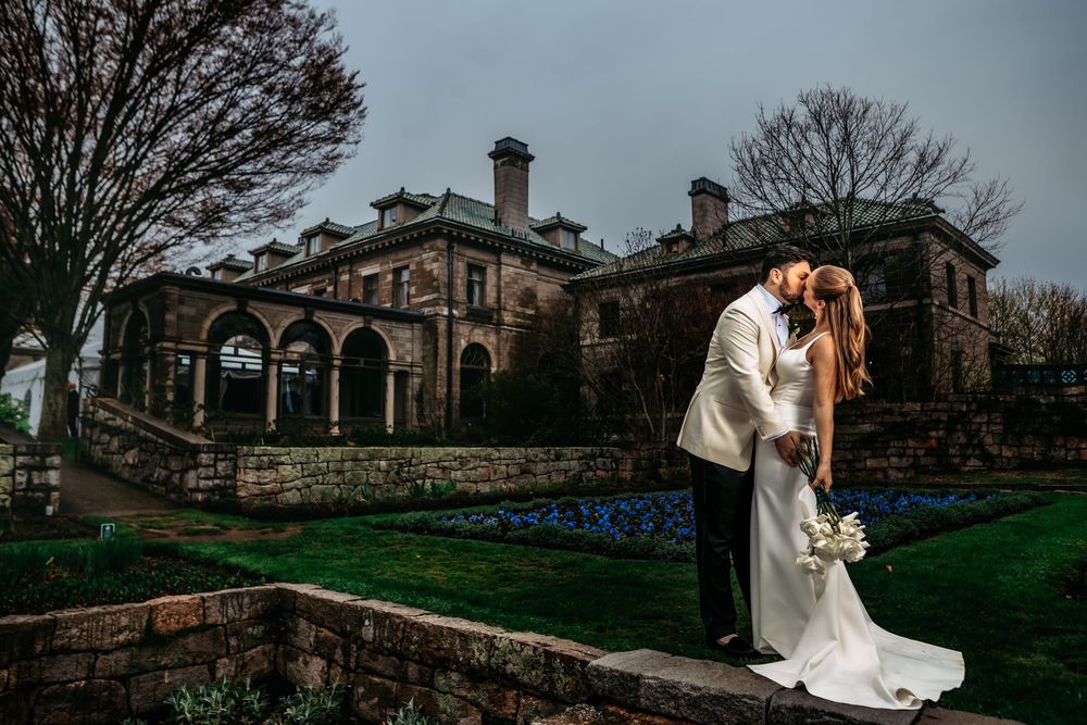 A series of romantic wedding photos captured at a historic stone building with elegant architecture and landscaping.