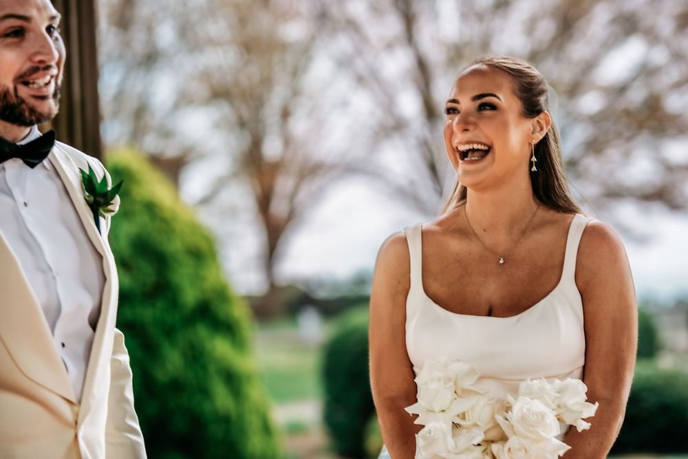 A joyful bride and groom share a candid moment together during their outdoor wedding celebration.