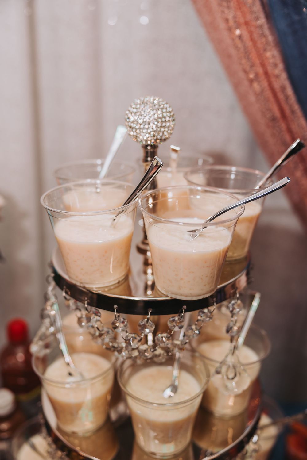 Elegant cocktail glasses filled with creamy beige-colored drinks arranged on a crystal serving stand.