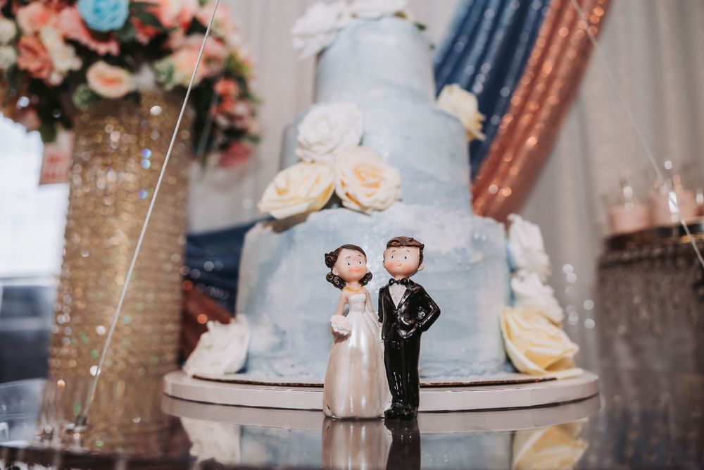A wedding cake decorated with white frosting and floral accents sits elegantly on a display table at a reception.