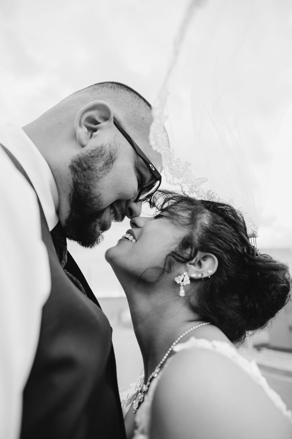 Black and white romantic wedding photography sequence showing intimate kiss between newlyweds in formal attire.