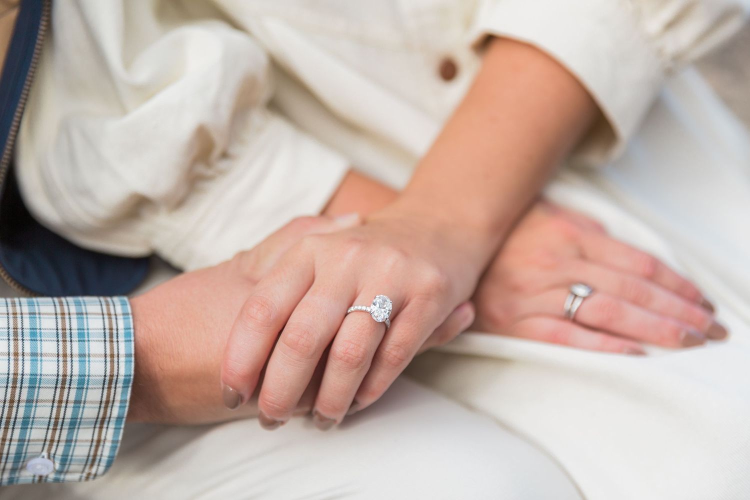 Close up view of a newly engaged couples' hands. Lady wearing a large oval diamond ring in Bibury Cotswolds. Proposal photographer