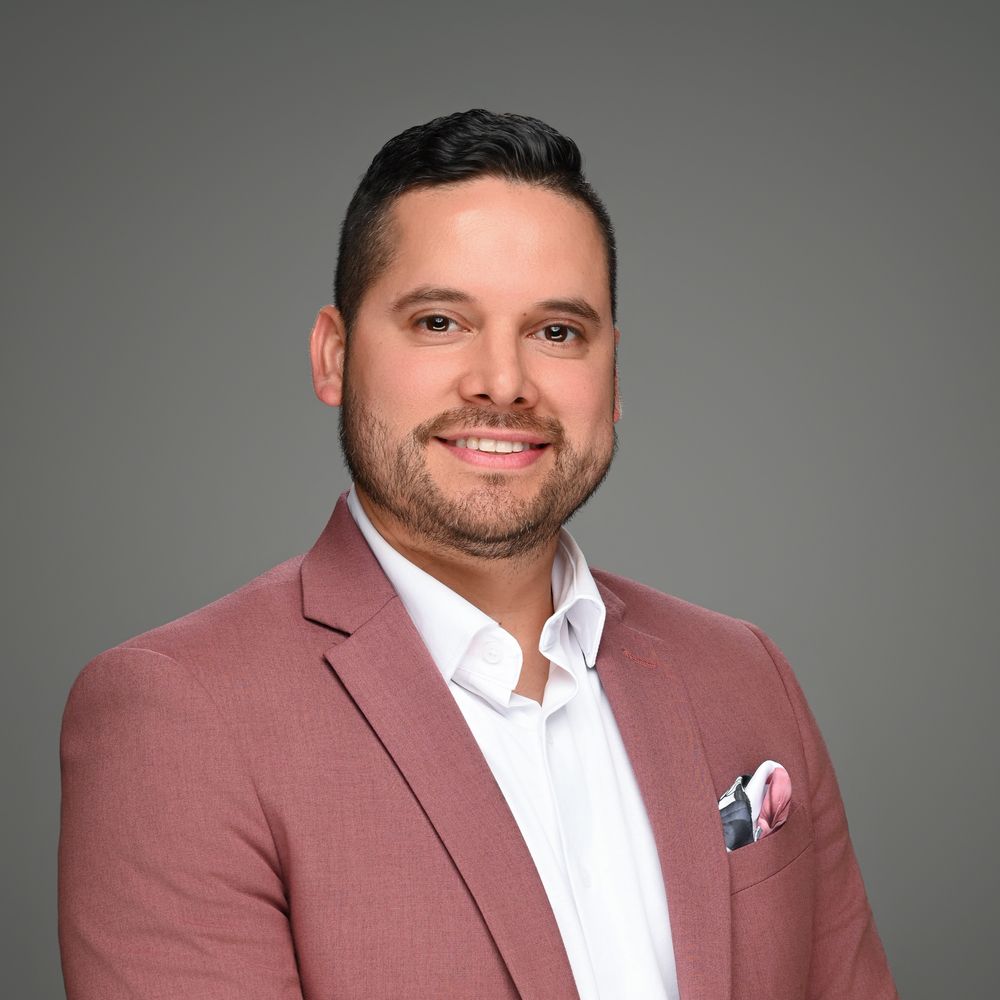 Professional headshots of person wearing mauve blazer and white shirt against grey background.