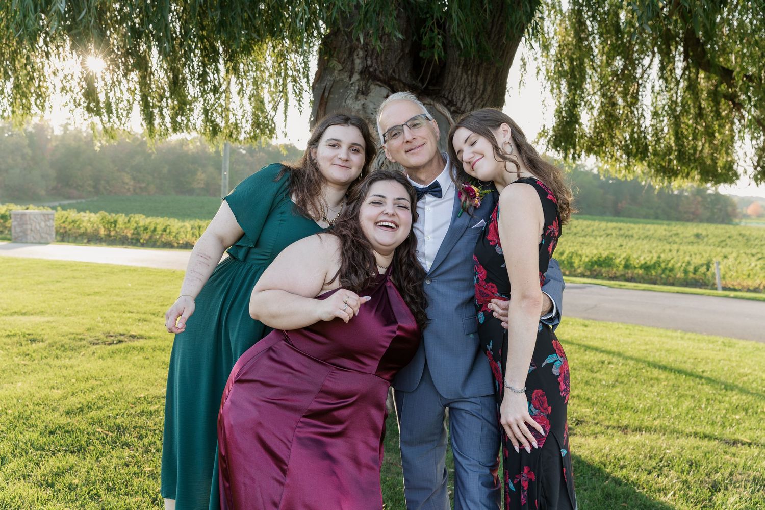Groom and his daughters pose for a fun portrait under the grand willow tree at Vineland Estates Winery.