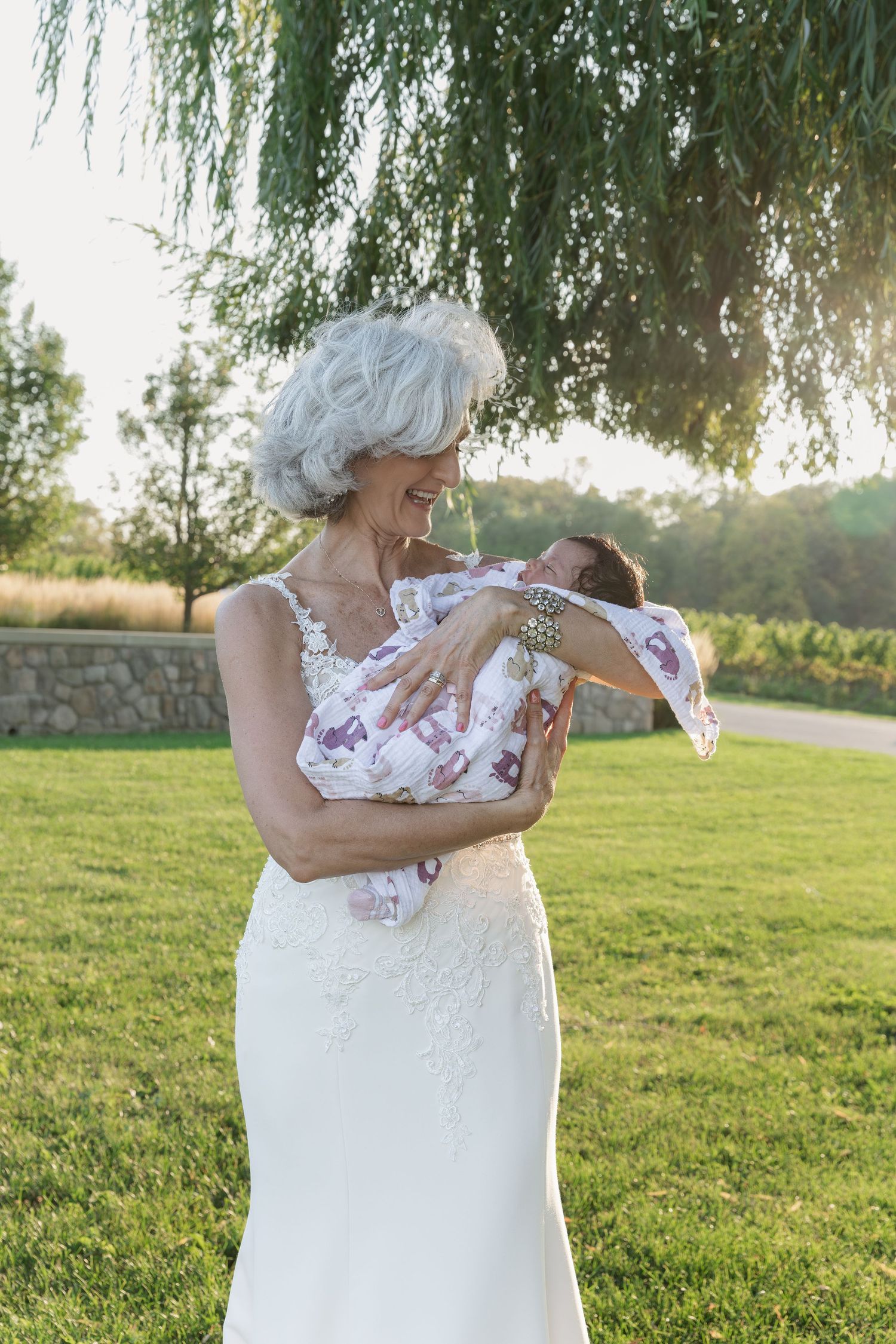 A tender moment of a bride under a weeping willow tree holding her granddaughter at Vineland Estates Winery.
