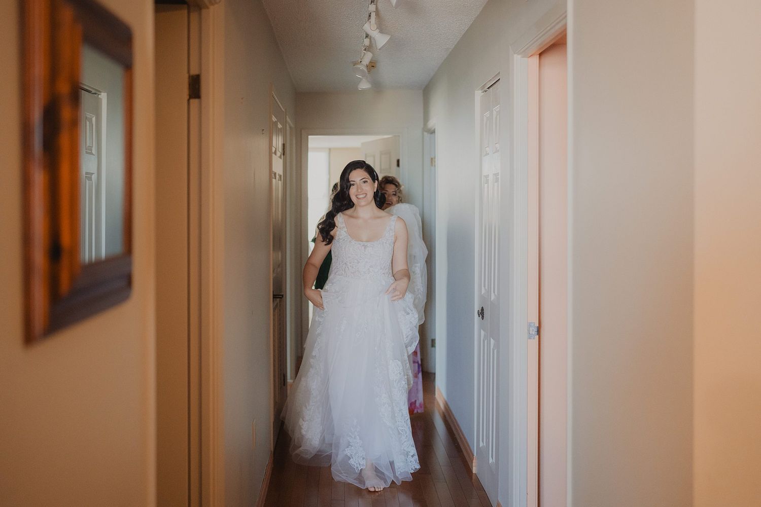 A flowing white wedding dress captured in a hallway with natural lighting.