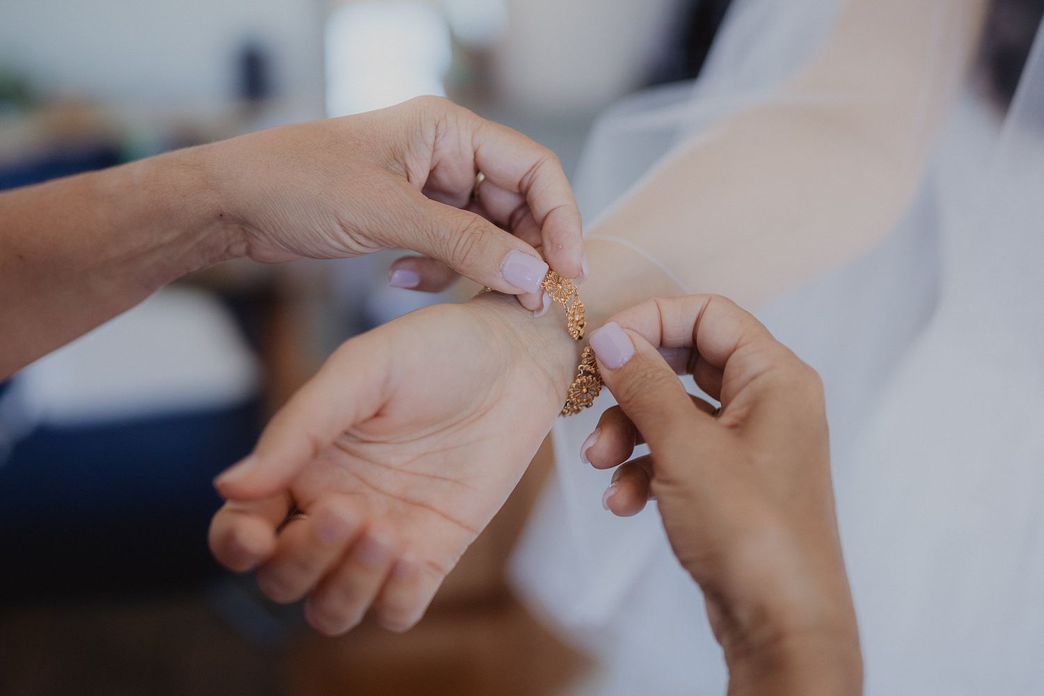 Close-up shot of hands fastening jewelry or accessories against a soft background.
