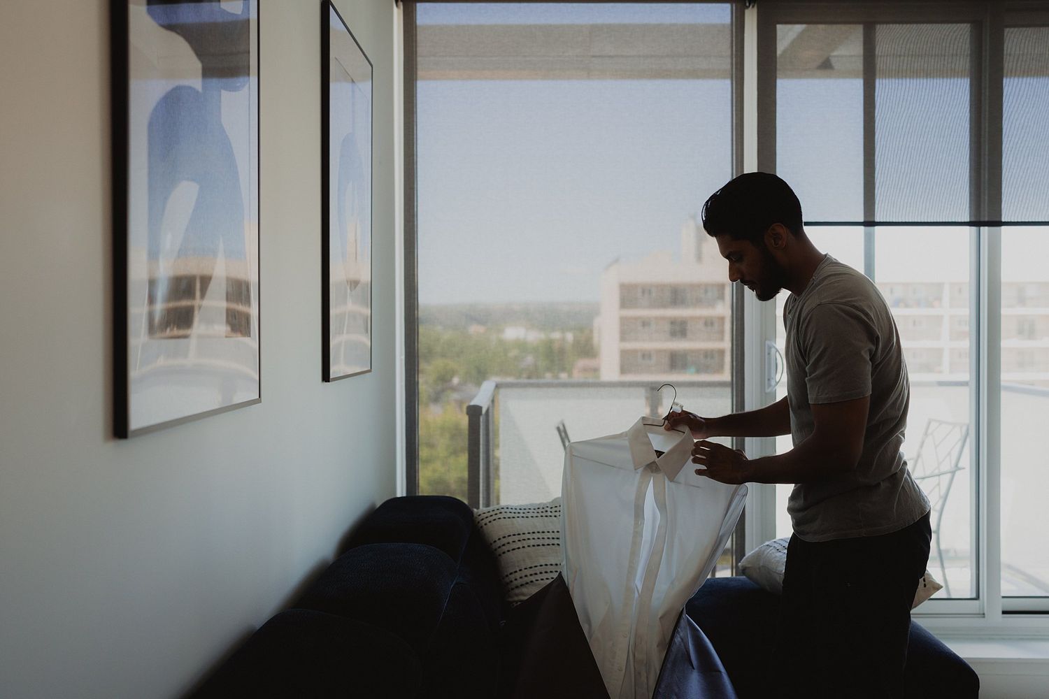 Silhouette of a person against large windows in a modern apartment setting.