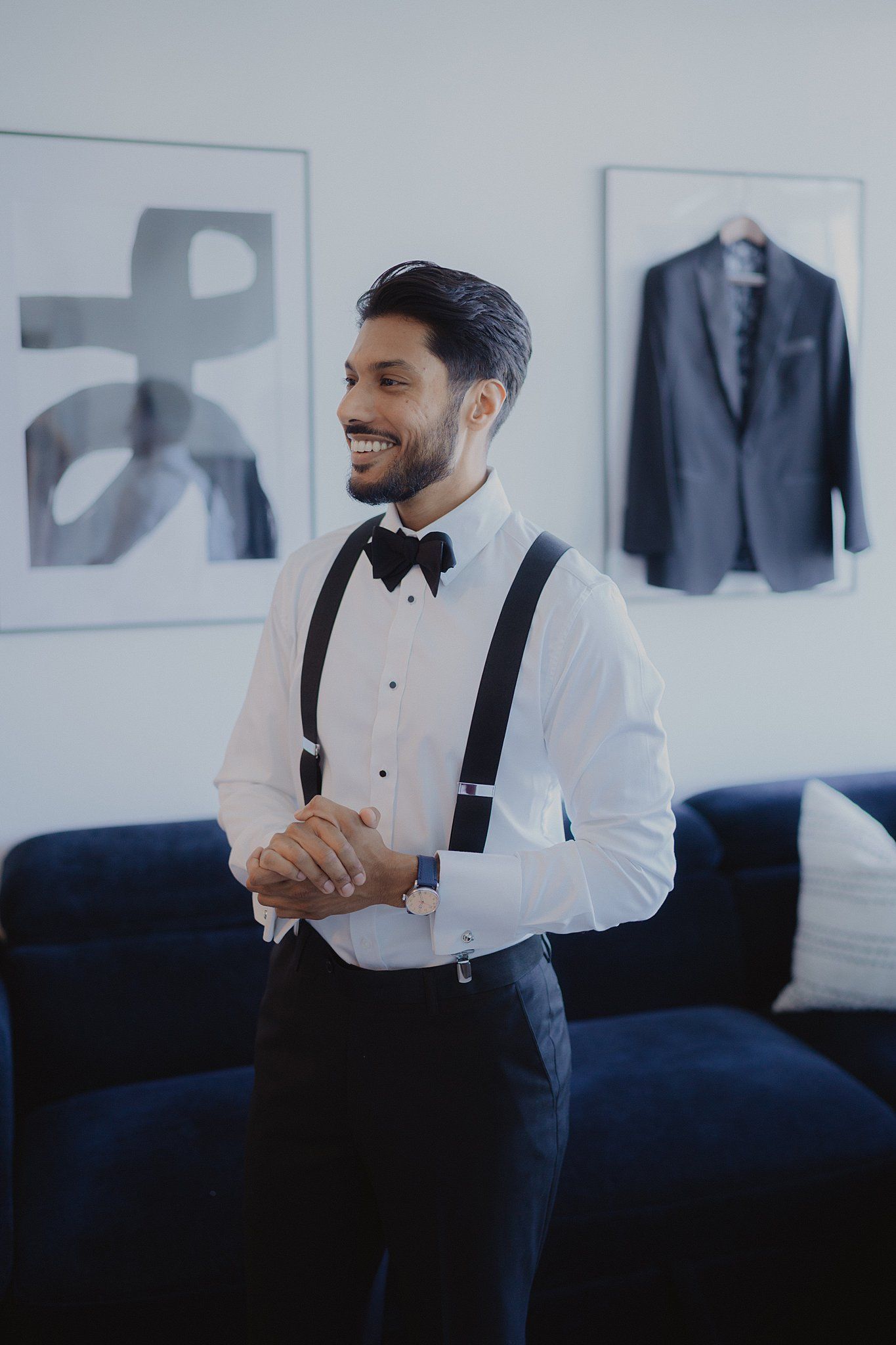 Formal attire preparation scene with bow tie and suspenders in an elegant room setting.