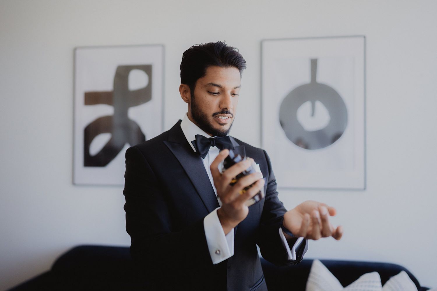 Side profile of person in formal attire sitting against white wall with modern decor.