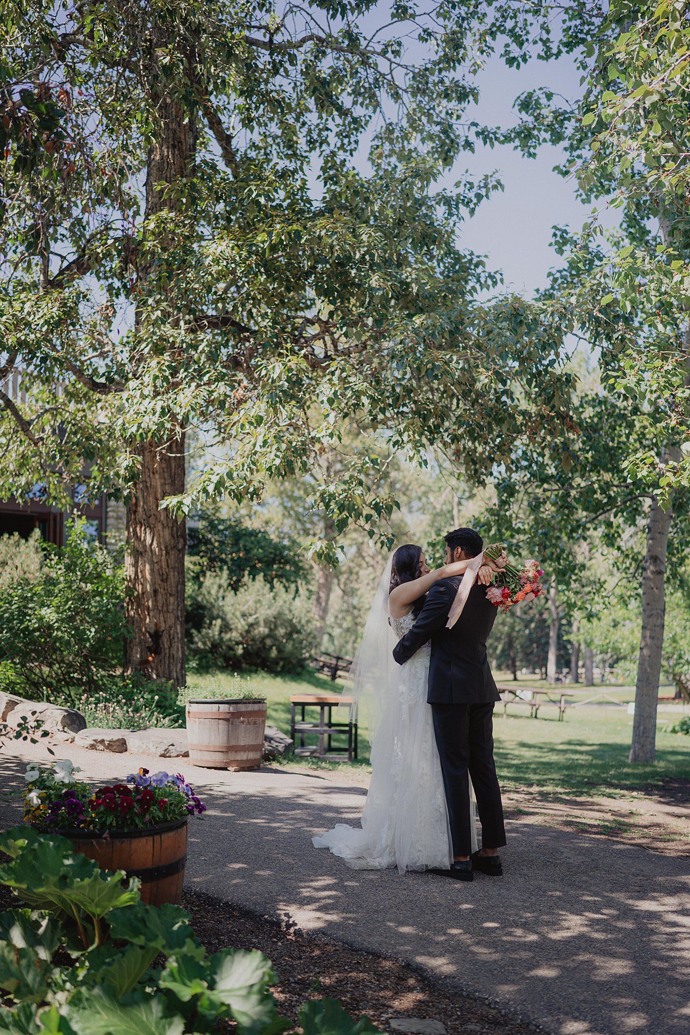 First look sequence in a garden setting with trees and flowering plants creating a romantic atmosphere.