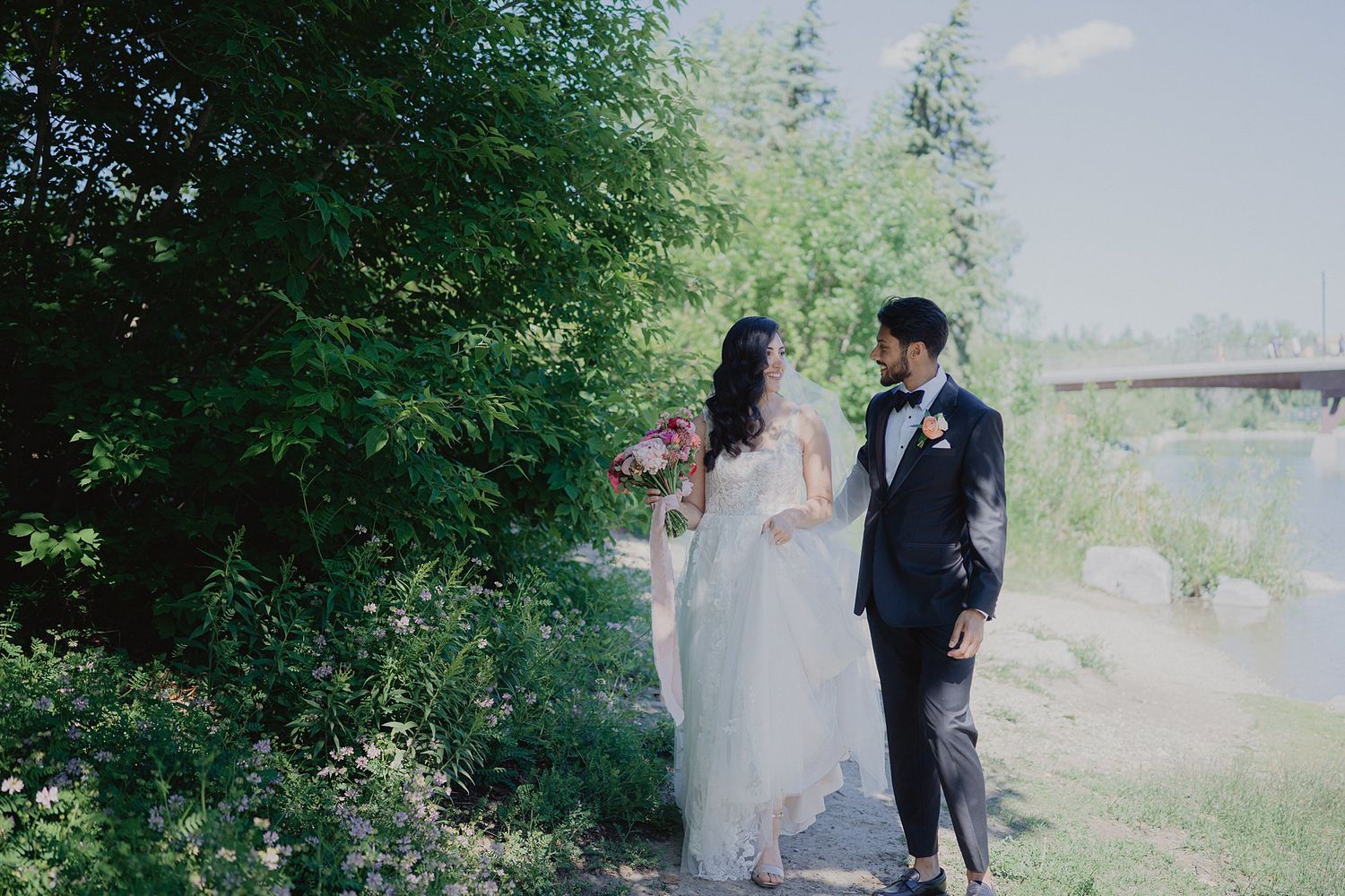 A romantic wedding couple poses together in a lush garden setting with beautiful natural lighting.