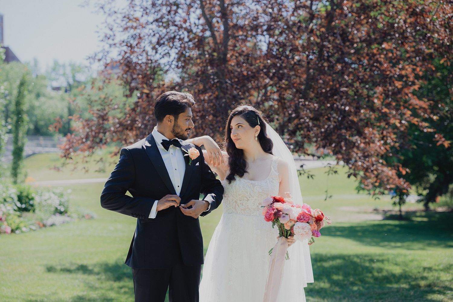 Wedding couple shares intimate moments under blooming trees in an outdoor garden setting.