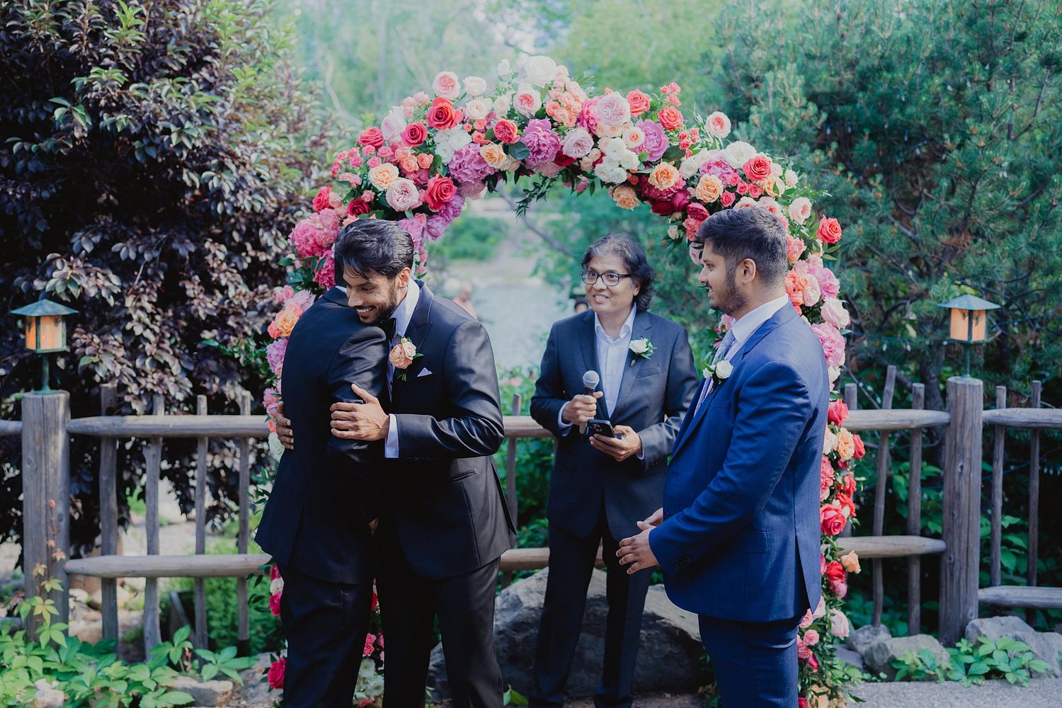 Vibrant floral arrangements with pink and red blooms decorate an outdoor garden venue.