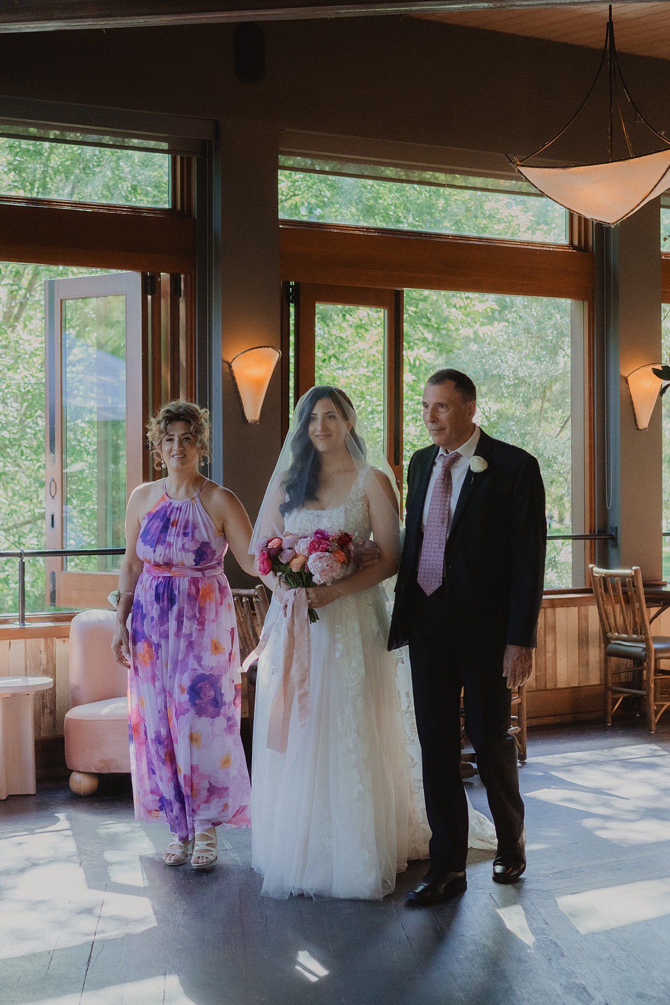 Wedding ceremony in a bright indoor venue with large windows overlooking nature.