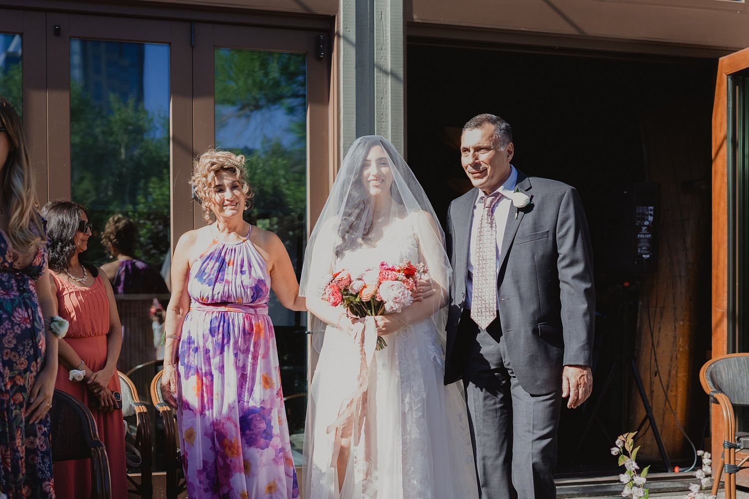 Wedding ceremony guests gather inside a venue with natural lighting.