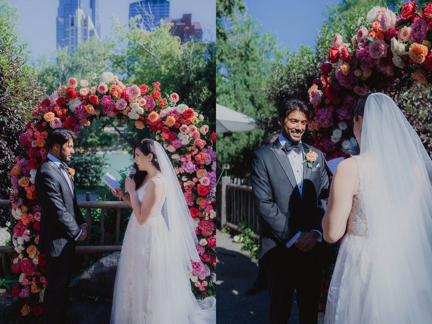 Wedding ceremony under a floral arch with pink and red roses in an outdoor garden setting.