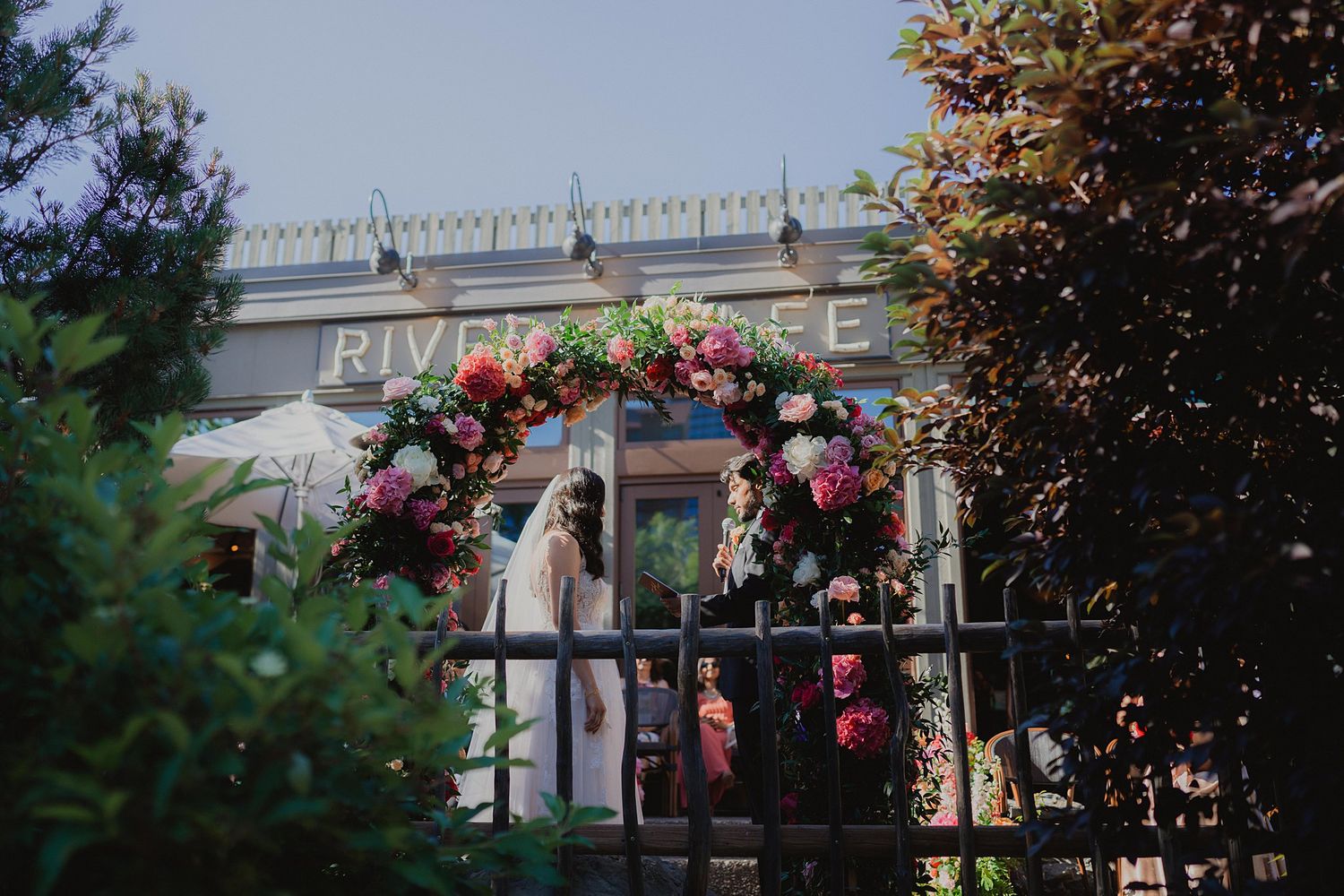 Riverside venue decorated with elegant floral arrangements and outdoor seating for a wedding celebration.