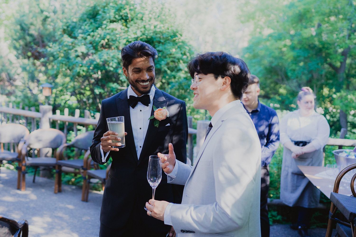 Wedding celebration toasts with wine glasses clinking during an outdoor reception.