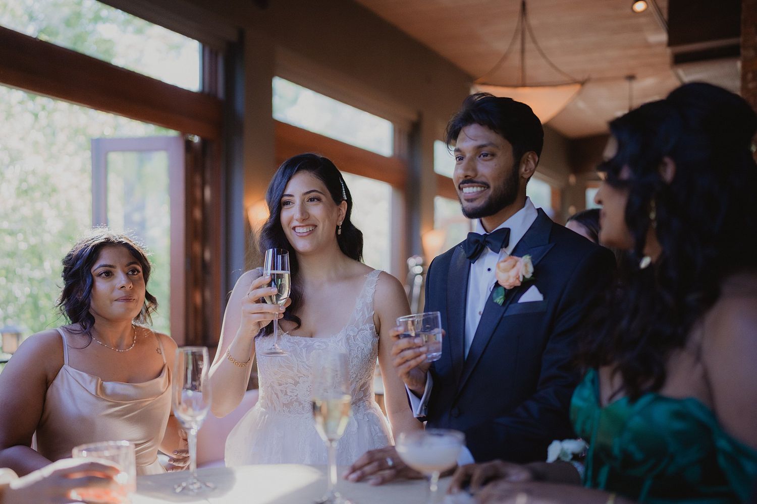 Wedding guests raise champagne glasses in celebration during an indoor reception.