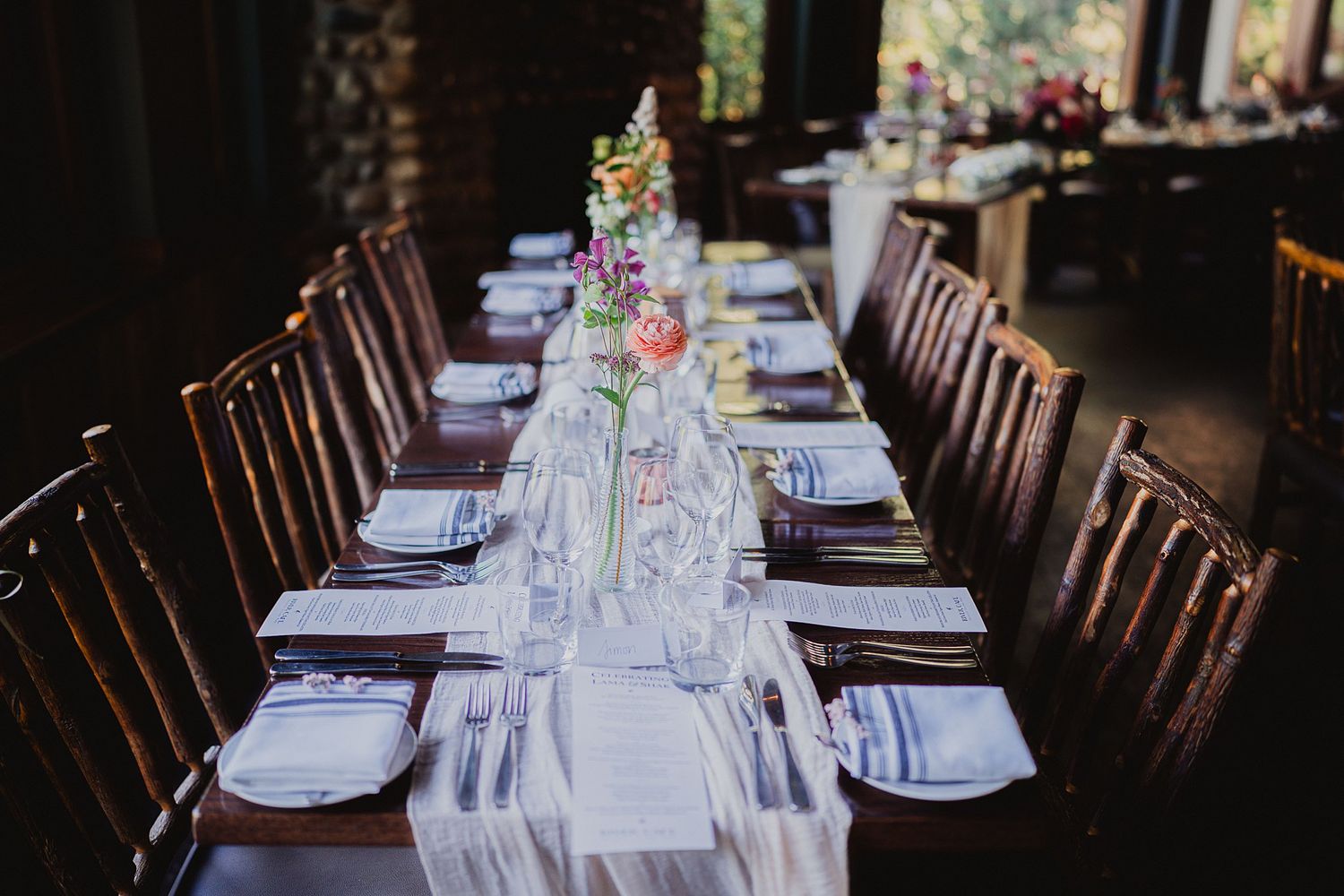 Elegant wedding reception table setting with dark wood chairs and white linens.