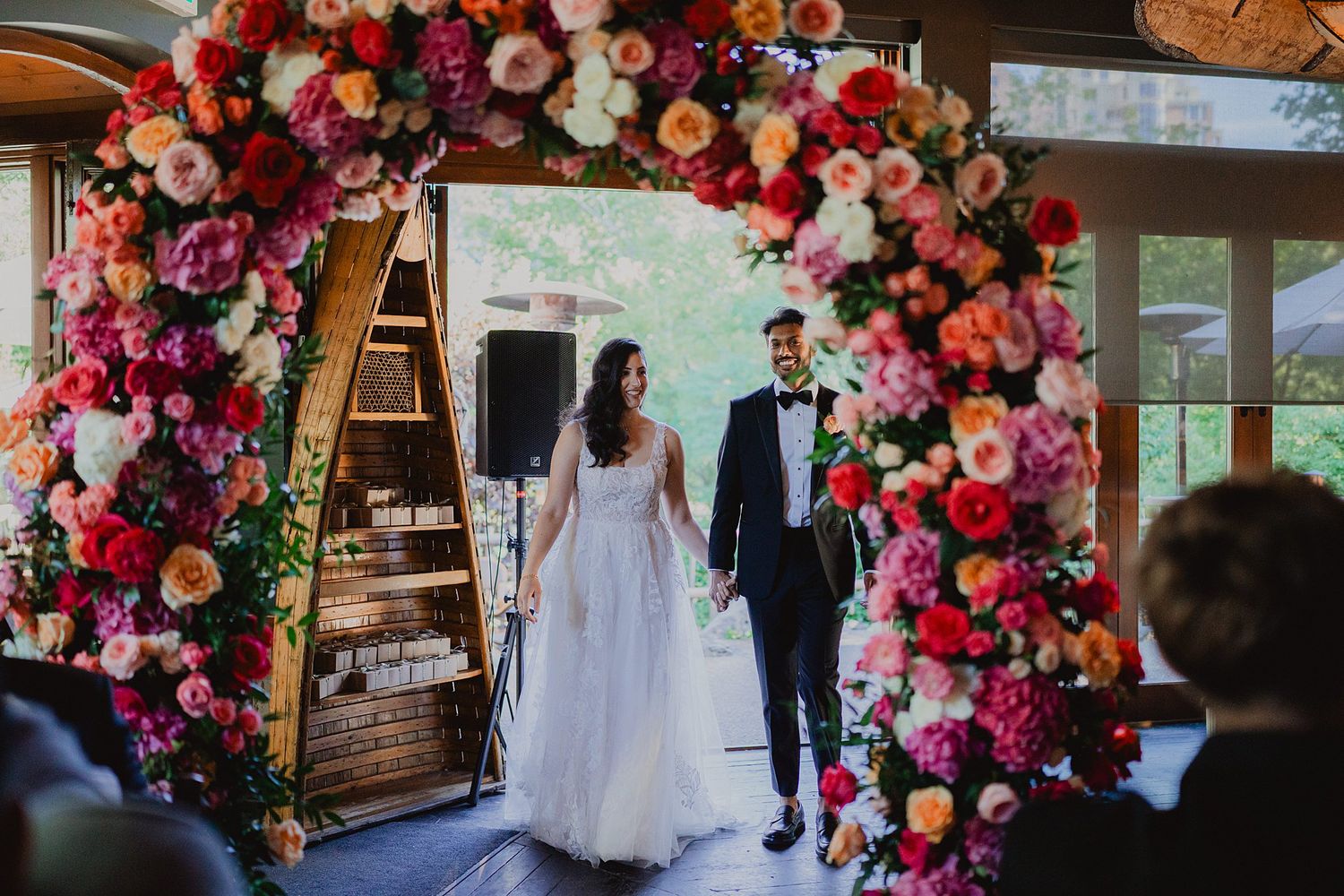 Elegant floral arch with pink and red roses creates a romantic wedding ceremony backdrop.