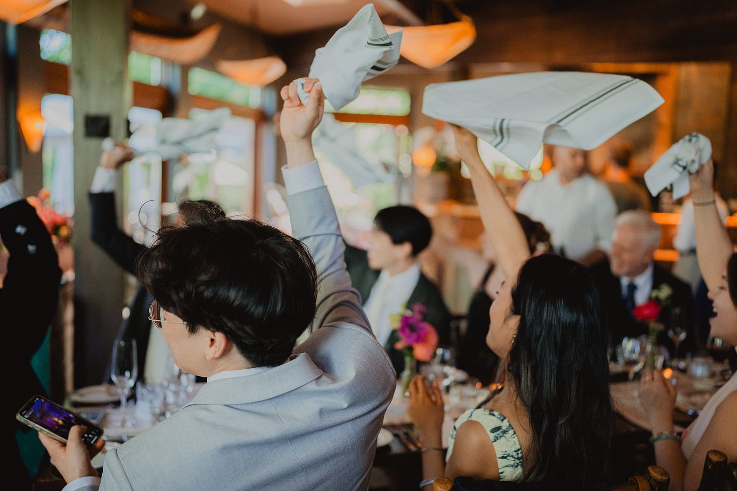 Wedding guests raising their hands in celebration during a reception event.