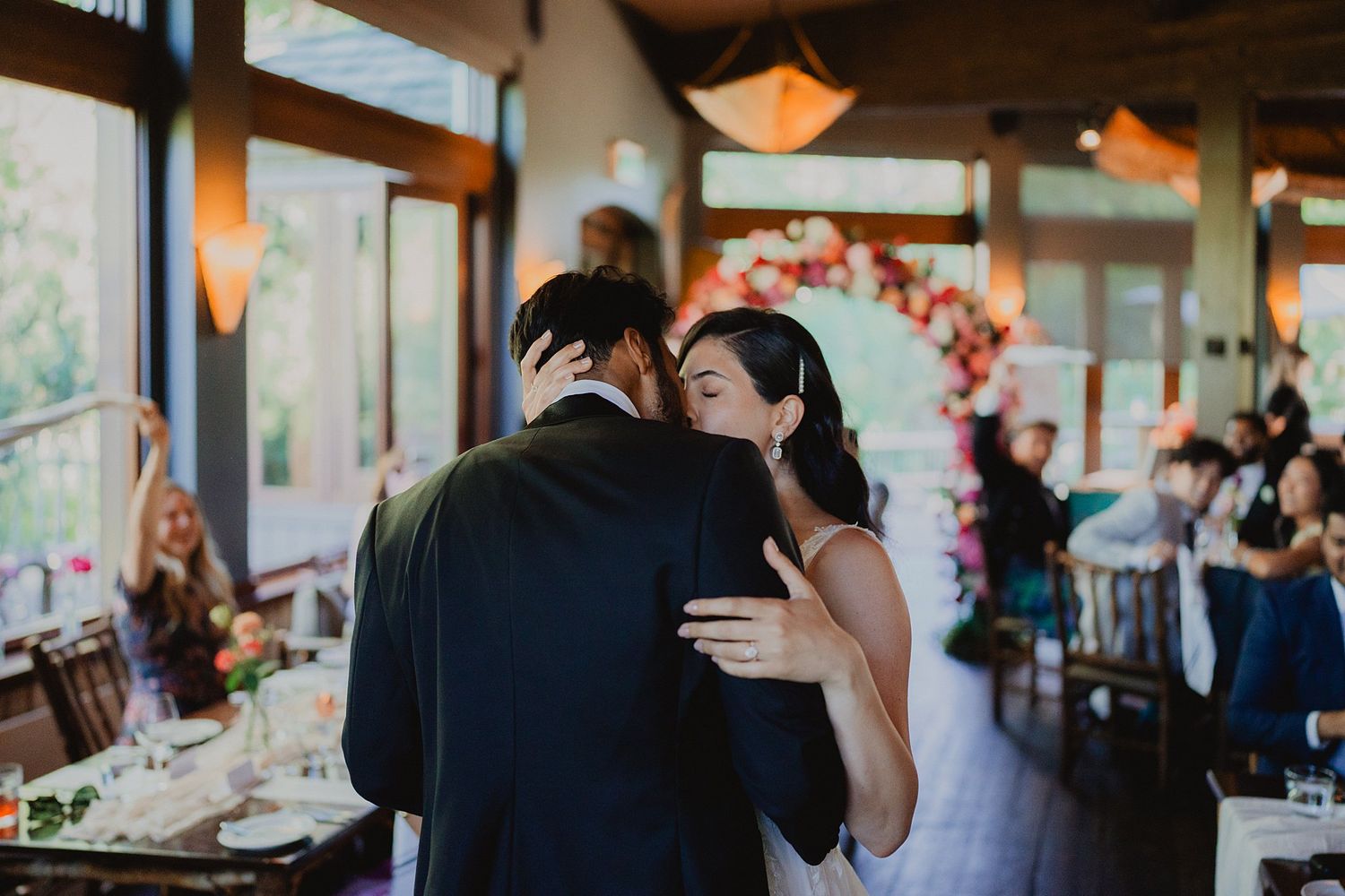 Wedding reception guests mingling and socializing in a warmly lit indoor venue.