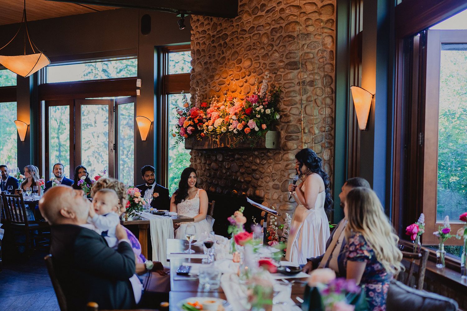 Wedding reception venue with exposed brick walls and large windows illuminated by warm ambient lighting.