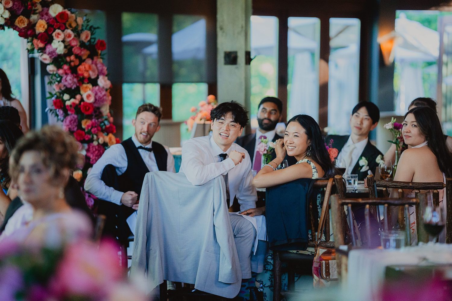 Wedding reception guests laughing and enjoying emotional speeches in a beautifully decorated venue.